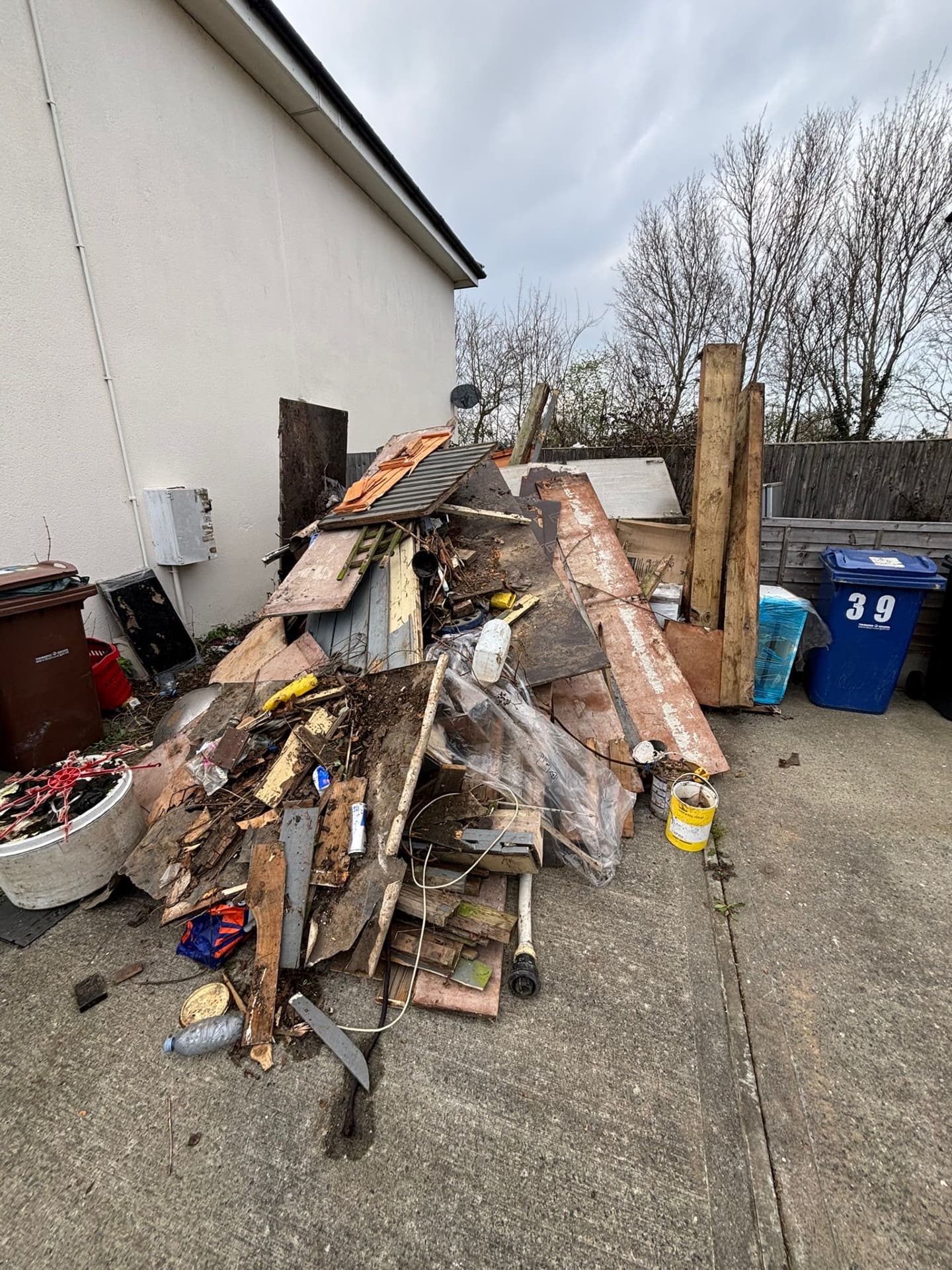 Driveway piled with wood, debris and corrugated sheets before clearance