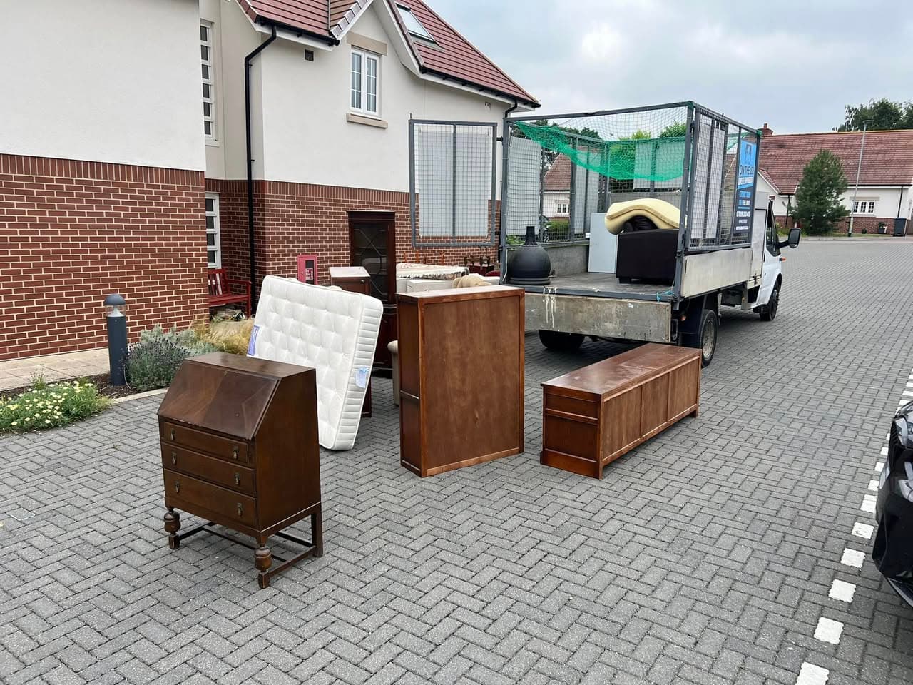 Furniture including bureau, mattress and cabinets on driveway ready for removal
